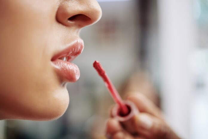 Applying gloss on plump lips