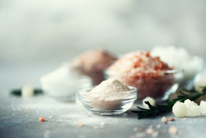 Mix of different salt types on grey concrete background. Sea salts, black and pink Himalayan salt